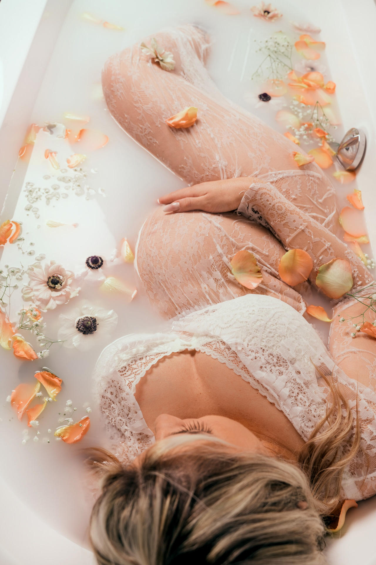 Femme enceinte dans bain de lait avec fleurs tons clairs 