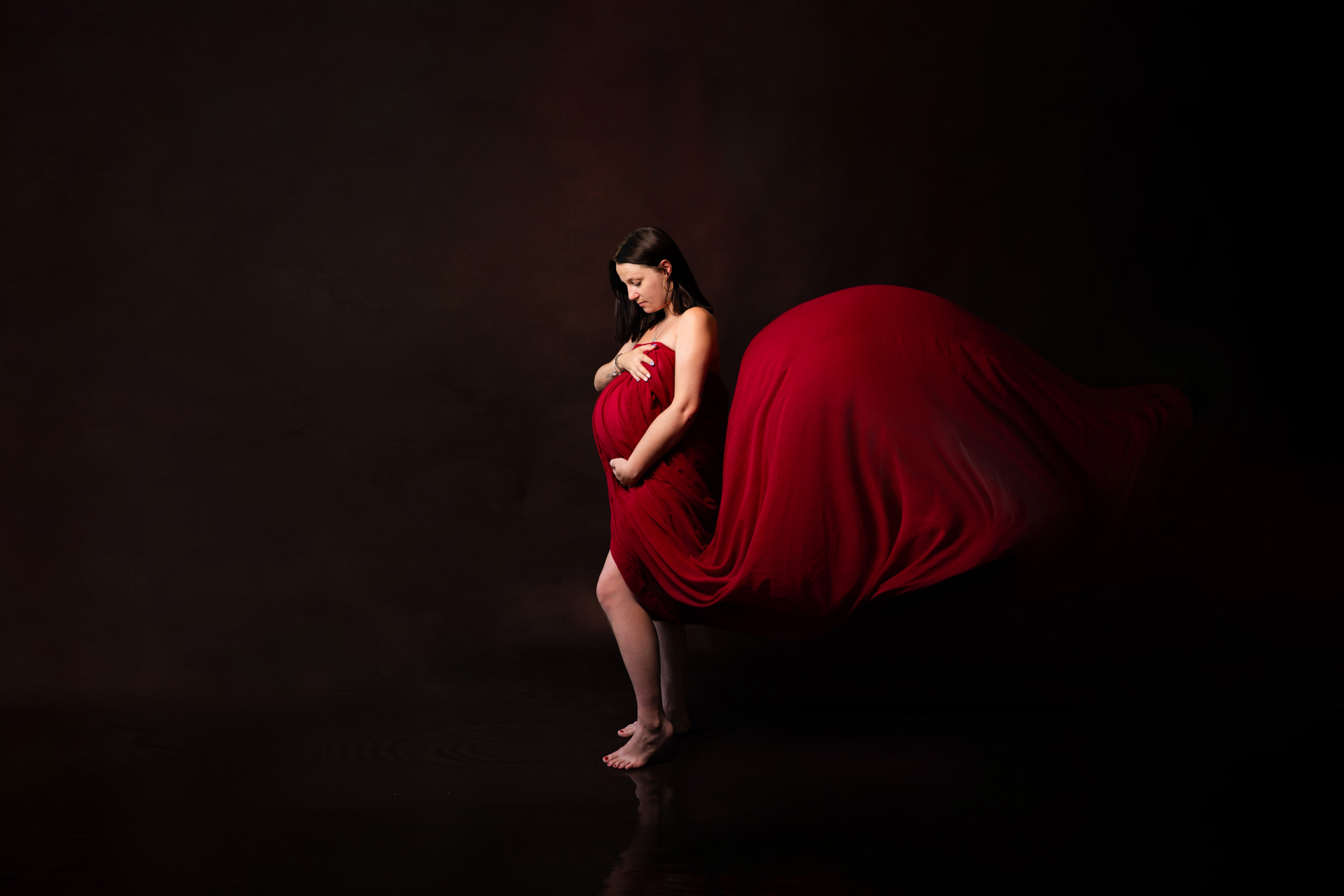 Grossesse studio fond noir robe rouge drapé